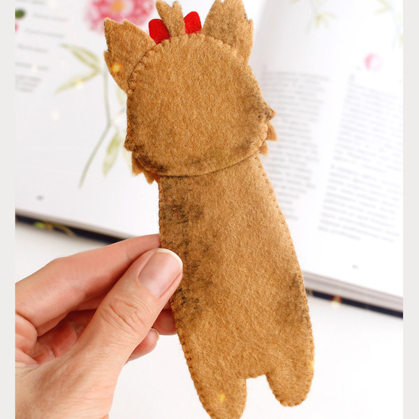 DIY felt hand sewn craft - kids long Yorkshire terrier dog hound bookmark in authors hand in front of the opened book, back side