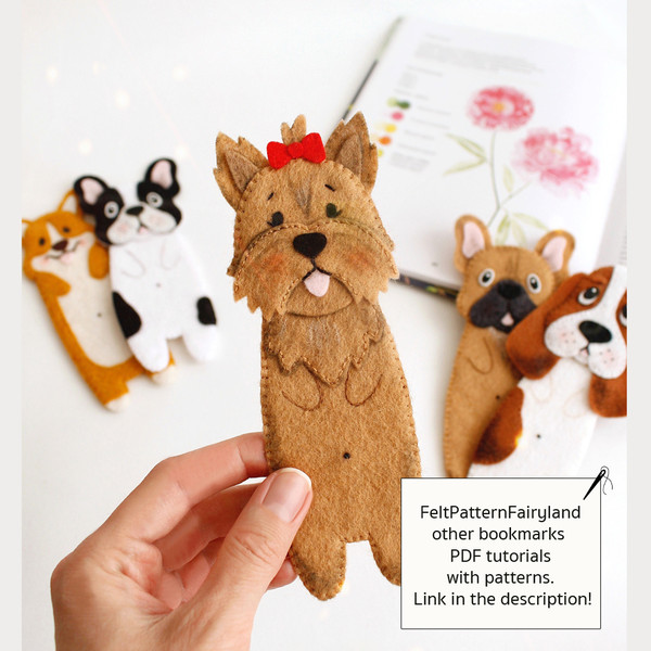 DIY felt hand sewn craft - kids long Yorkshire terrier, Basset hound, corgi and French bulldogs dogs bookmark in authors hand in front of the opened book and ot