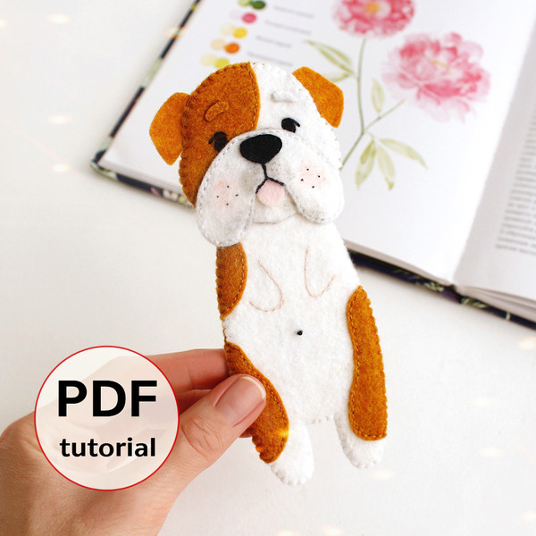 DIY felt hand sewn craft - kids long English bulldog bookmark in authors hand in front of the opened book