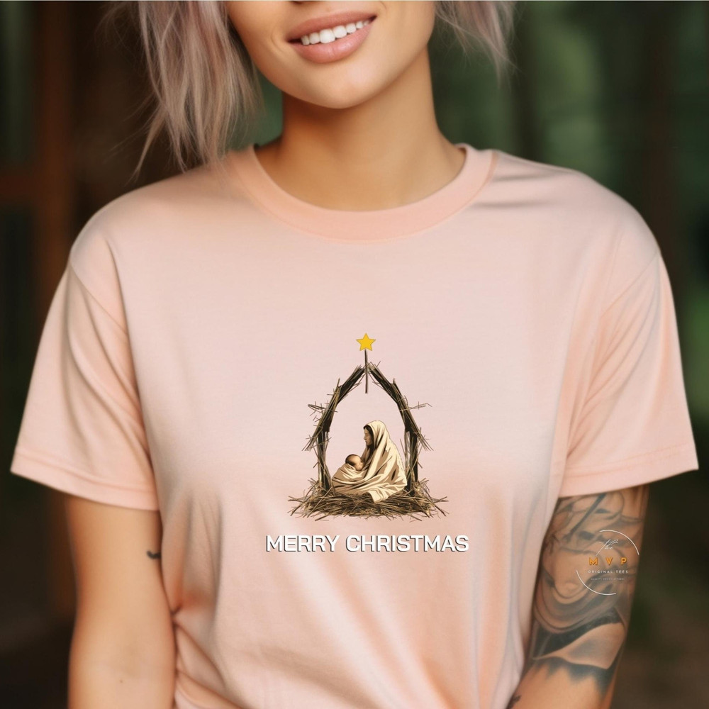 A Merry Christmas T-shirt that pictures, the First Christmas there’s a high-quality drawing of Mary and baby Jesus in a simple manger scene..jpg