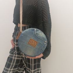 a cute round denim purse with 2 pockets on the outside and 2 pockets inside, has an adjustable beige strap up to 155 cm
